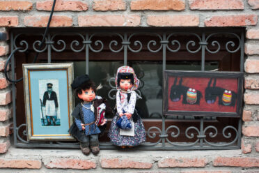 Small dolls in traditional Georgian cloths and paintings in vendor's window in Tbilisi, Georgia.