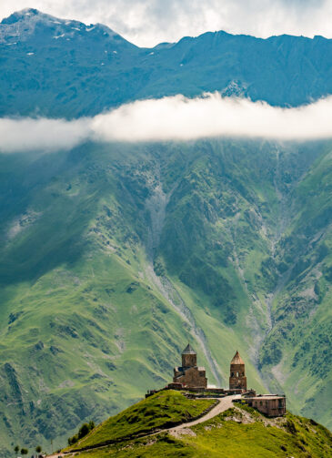 The 14th century Gergeti Trinity Church watches over the Caucasus Mountains. Near Kazbegi, Georgia.