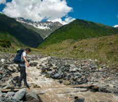 Man crossing river on timber plank bridge on trail from Mestia to Ushgali in Georgia's Svaneti region.
