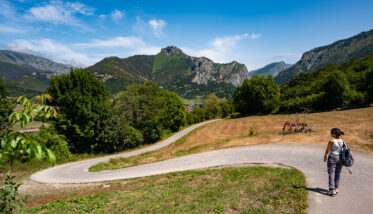 Woman hiking along quiet, winding road in mountains near Arenas De Cabrales, Asturias, Spain