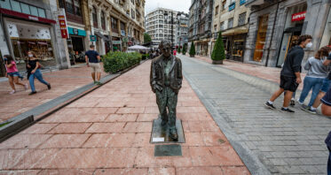 Oviedo, Austurias, Spain - August 10, 2020: Bronze statue of Woody Allen designed by Spanish sculptor Vincente Menendez Santarua on a pedestrian walkway.