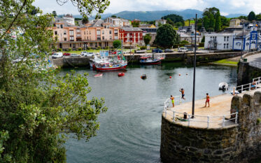 Children jumping from breakwater in harbor of Puerto de Alba, Asturias, Spain