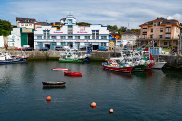 Puerto de Vega, Asturias, Spain - 14 August 2020: Harbor with fishing boats and seaside restaurant