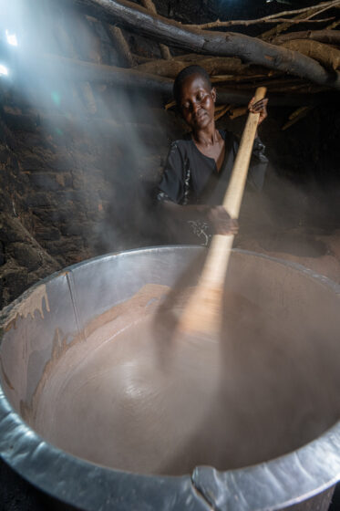 Namutesi Zeda cooks the grain amaranth composite porridge at an Iowa State University Uganda Program (ISU-UP/IOWA) mothers' group. She works the wooden paddle through the thickening mix – millet, grain amaranth, soybean and maize, with silver fish, sugar and milk – in the smoke of the centre's kitchen. The women meet once a week to share a feed and carry home a kilogram of the flour, enough to cook the supplementary porridge for their families over the following days.
Photo: Michael Major for Crop Trust