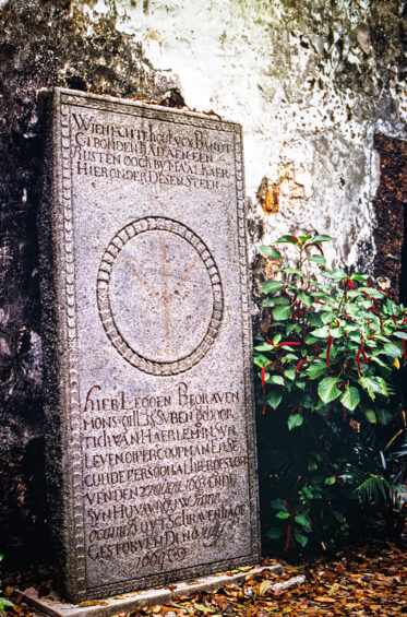 A weathered 17th-century Dutch tombstone in the grounds of St Paul's Church, Malacca, its inscription still legible after three hundred years of tropical weather.