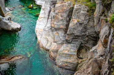 Colored stone and emerald waters of the Verzasca River near the village of Lavertezzo in the Swiss canton of Ticino.